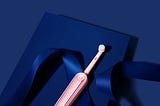 Pink electric toothbrush on a deep blue background