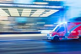 An ambulance speeding down the road. The photo is a bit blurry to show the action.