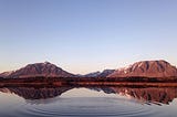 A quiet lake with ripples where it was disturbed.