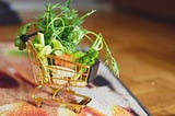 Tiny shopping cart filled with bits and pieces of vegetables.