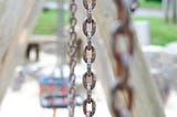 the chain from a swing, at a playground, other swings faintly seen in the background, Leah Welborn, Mediun