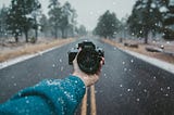 a hand holding a camera in a snowy day with mist