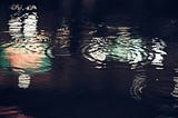 raindrops in a pool of water at night