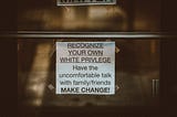 A sign taped to a wall that reads “Recognize your own white privilege. Have the uncomfortable talk with family/friends. Make change!”