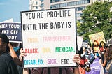 Pro-abortion rally with protestor holding sign that reads: You’re pro-life until the baby is poor, transgender, Black, gay, Mexican, disabled, sick, etc…”
