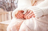 Woman in white sweater sitting with hands curled in uncertainty