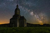 A wooden chapel under star-filled night