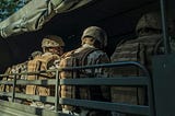 A bunch of soldiers sitting in military fatiques, in a truck