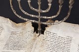 A menorah with an ancient manuscript.