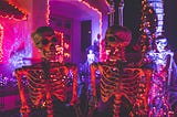 Colour photo of a pair of life-size decorative skeletons outside a house decorated for Halloween