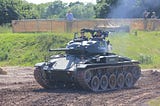 A tank driving with two soldiers looking out