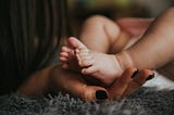 Kid’s feet on mother’s palm