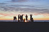 a group of people enjoying a bonfire at sunset