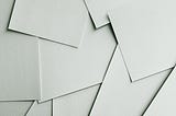 Many pieces of white paper on a table, just strewn about.