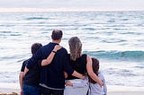 Family with back turned looking at the lake. Mother, father and two children