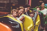 Mothers and children in a moving roller-coaster. Everyone excited, except for the one little girl right up in front — she’s terrified!