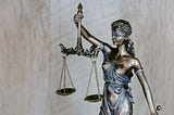 An iron statue of a woman blindfolded and holding the symbol of justice.