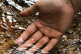 Right palm with water gently flowing over the fingertips.