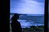Lone woman staring at the ocean at dusk