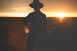 Man playing the banjo at sunset.