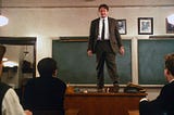 Photo of Robin Williams standing on his desk in Dead Poets Society.