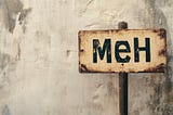 Beat up sign that says “meh” against a dirty concrete wall