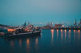 A ship docked in a port with lights reflecting on the water.