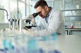 Male researcher analyzes sample under microscope — Invitae blog