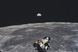A surface of the moon with a space vehicle on it, and the Earth in the background.