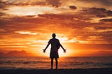 man on a beach, silhouetted against the sun