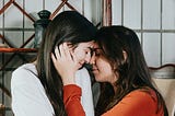 two girls cuddling with their noses touching and they look like they are in love