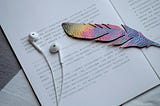 A quill-shaped cutout and headphones on a printed page