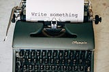old typewriter with a sheet that says write something