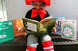A child reading a Dr. Seuss book surrounded by his most popular titles.
