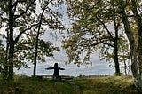 Person sitting by themselves on a bench in the woods