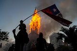 Igreja de Assunção sendo incendiada no Chile e manifestantes comemorando.