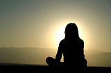 a woman sitting and watching the sunset