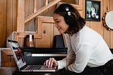 Woman listening to music on headphones in front of a laptop