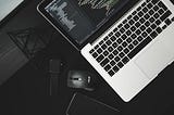 Aerial view of laptop and mouse on dark colored desk