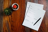 paperwork sitting on a desk with a pen on top of it