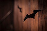 A Batman batarang stuck inside a wooden wall.
