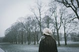 Photo of the back of a woman walking as snow is falling