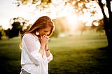 Woman with hands clasped, bowing head in prayer