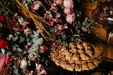 A cake in a glass dish, with wild flowers and leaves next to it