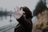 A woman signalling “stop” with her palm facing the camera