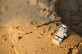 Lego storm trooper sitting in the sand while contemplating life.