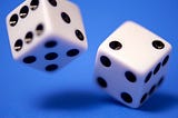 A standard set of dice midroll against a blue background.