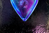 A translucent blue, heart-shape crystal floating on a rock surface