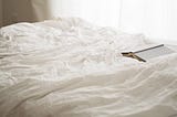 crumpled bedsheets and an open book
