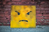 Angry square in front of a brick wall